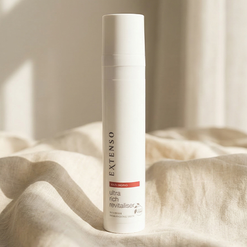 Extenso Ultra Rich Revitaliser flacon staand op een zachte beige linnen doek in warm natuurlijk licht