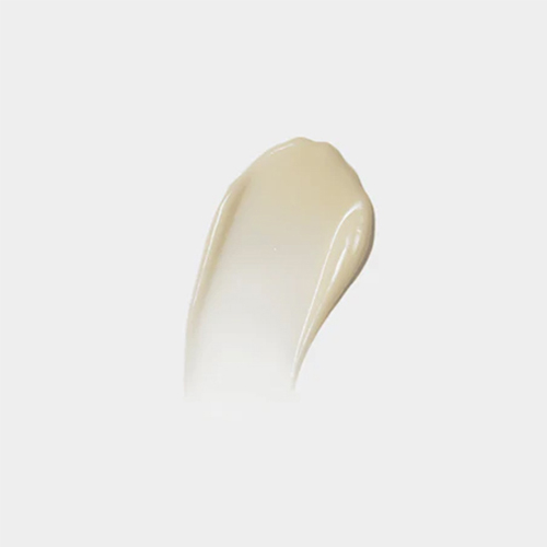 Een uitgesmeerde veeg van de romige, licht beige iS CLINICAL Brightening Complex gezichtscrème op een egale grijze achtergrond.