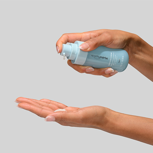 Hand die serum uit de HydroPeptide Soothing Serum pompflacon op de handpalm pompt