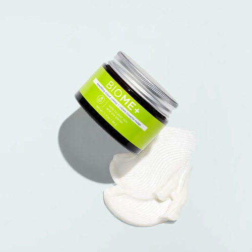 De BIOME+ Smoothing Cloud Crème verpakking naast een luchtige swatch van de hydraterende gezichtscrème.