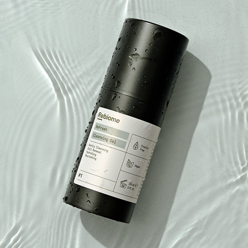 Natte fles Rebiome ReFresh reinigingsgel van 150 milliliter liggend in helder water met waterrimpels