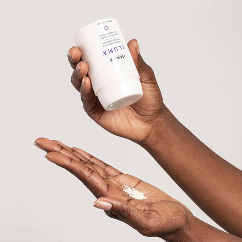 Iemand strooit het Image Skincare Iluma Intense Brightening Exfoliating Powder vanuit de flacon in een handpalm voor gebruik.