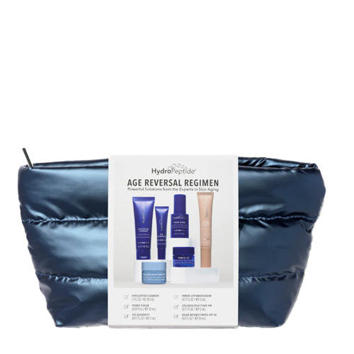 De complete HydroPeptide Age Reversal Regimen huidverzorgingsset gepresenteerd in een luxe, gewatteerde blauwe travel-bag met een informatieve wikkel aan de voorzijde.