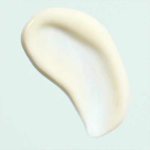 Close-up van de vloeibare, witte en lichtglanzende textuur van het IMAGE Skincare Sun Serum op een lichtblauwe ondergrond.