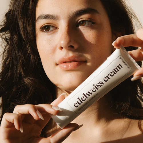 Model met donker haar en sproeten dat een tube prescription edelweiss cream vasthoudt