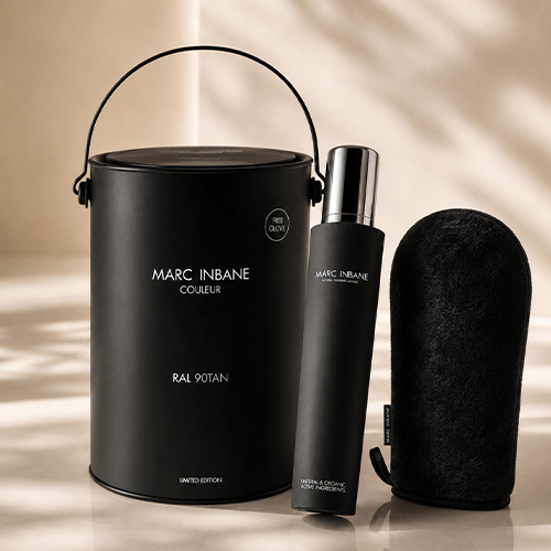 Sfeerbeeld van de Marc Inbane RAL 90TAN geschenkset met de Natural Tanning Mousse fles een zwarte emmer en een tanning glove in een warm verlichte ruimte