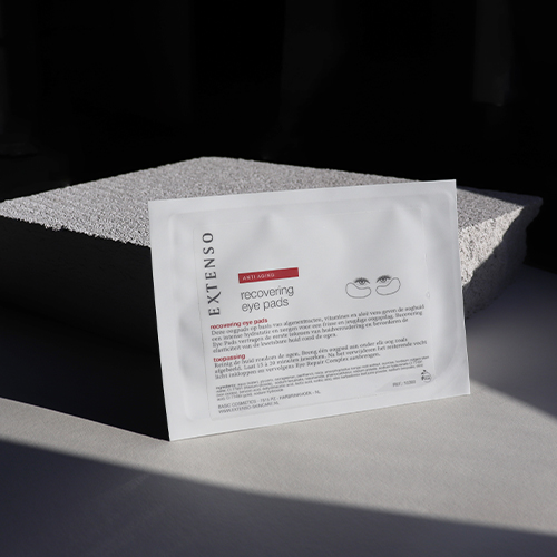 Extenso anti aging recovering eye pads verpakking rustend tegen een ruwe grijze steen in sfeervol zonlicht