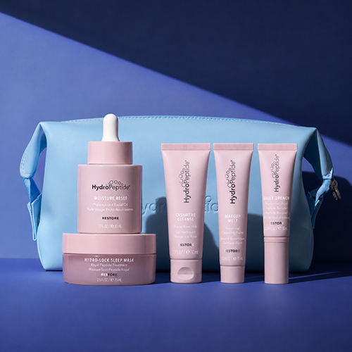 De lichtblauwe toilettas en vijf roze HydroPeptide producten opgesteld tegen een blauwe achtergrond
