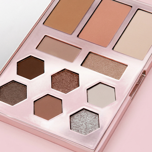 Close-up van de texturen in het gezichtspalet, variërend van matte bruintinten tot glinsterende metallic oogschaduws en poeders.