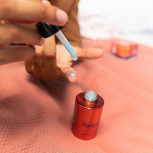Een blauwe druppel serum wordt aangebracht op een vinger met de pipet