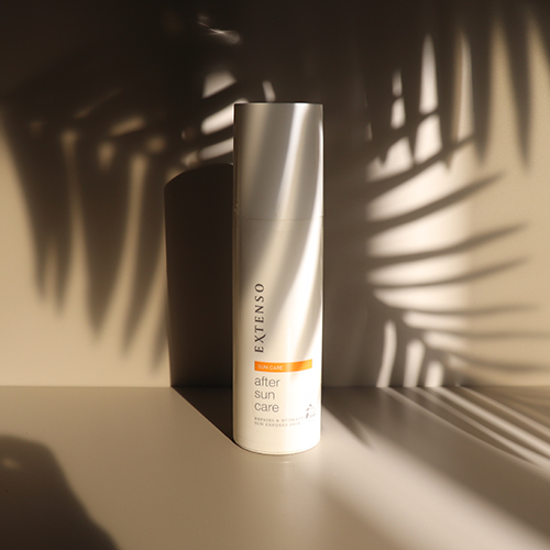 Een witte fles Extenso After Sun Care lotion op een beige oppervlak, met schaduwen van palmbladeren op de achtergrond.