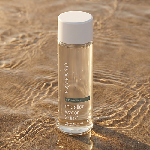 Een fles Extenso micellair water staand in ondiep, helder stromend water