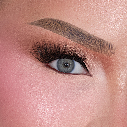 Close up van een opgemaakt oog met volle kunstwimpers en strakke wenkbrauw van Nimya