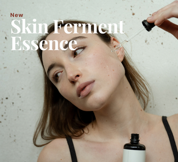 Een vrouw brengt met een pipet druppels van de Likami Skin Ferment Essence aan op haar gezicht, met de tekst New Skin Ferment Essence in beeld