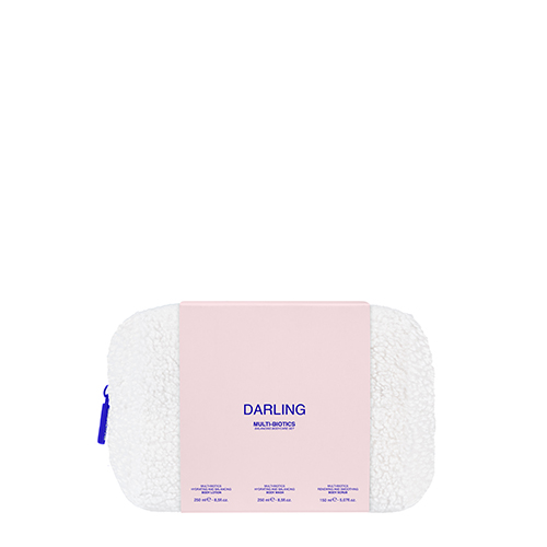 Een productfoto van de Darling Multi Biotics toilettas. Het is een witte, pluizige toilettas met een blauwe rits. Er zit een roze wikkel omheen met de merknaam "Darling" en de tekst "Multi Biotics".