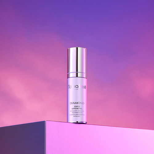 De zilveren flacon van de Glyco Extreme Peel staat op een strakke verhoging tegen een sfeervolle paarse achtergrond met roze lichtaccenten.