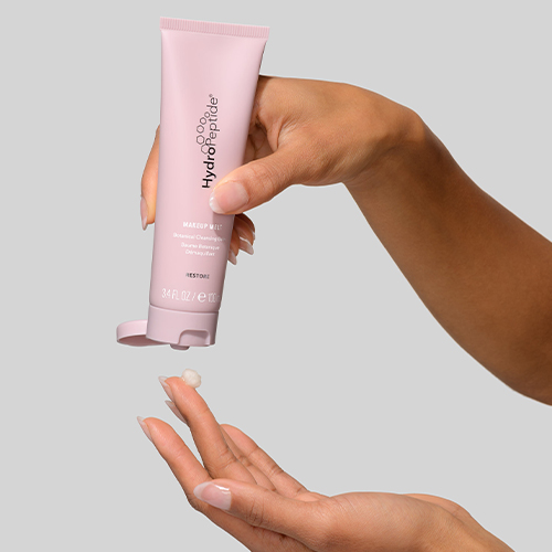 Handen die product knijpen uit een roze tube HydroPeptide Make Up Melt