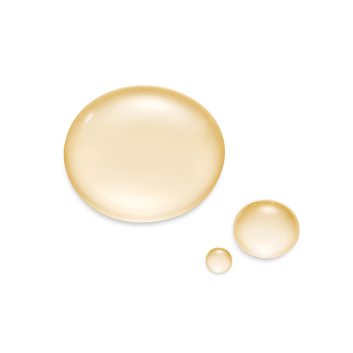 Drie vloeibare, lichtgele druppels van het Natura Bissé vitamine C serum op een witte ondergrond, variërend in grootte.