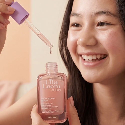 Een lachend meisje houdt een pipetje boven het geopende glazen flesje van het Lila Loom Loom Bloom Serum.