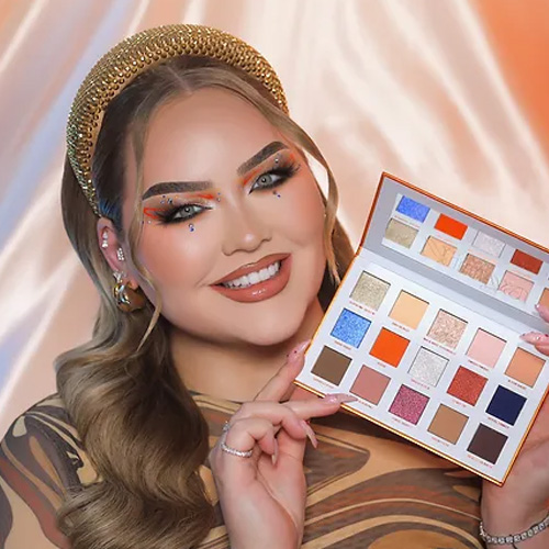 Nikkie de Jager met een gouden haarband en opgemaakte ogen toont het open Nimya oogschaduwpalet
