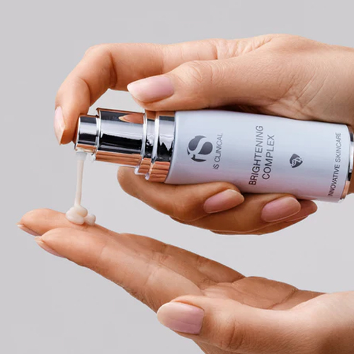 Iemand brengt iS CLINICAL Brightening Complex serum aan vanuit de pompflacon op de handpalm.