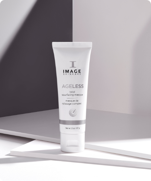Een witte tube van het IMAGE Skincare AGELESS total resurfacing masque, staand op een modern wit platform met strakke schaduwen.