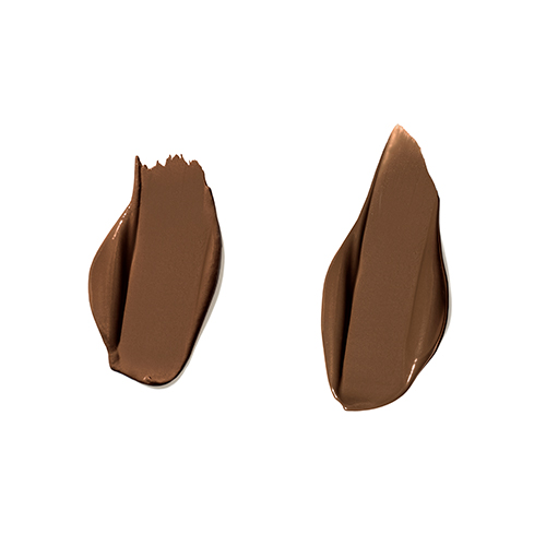 Twee romige vegen van Jane Iredale PureMatch Liquid Concealer in de kleur 15W Deeper op een witte achtergrond. De vloeibare textuur toont een zeer diepe, warme tint met een egale dekking