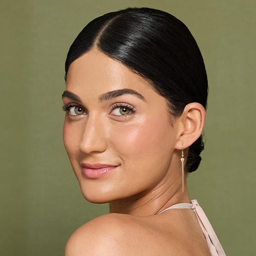 Model met een natuurlijke make-up look en glanzende lippenstift op een groene achtergrond