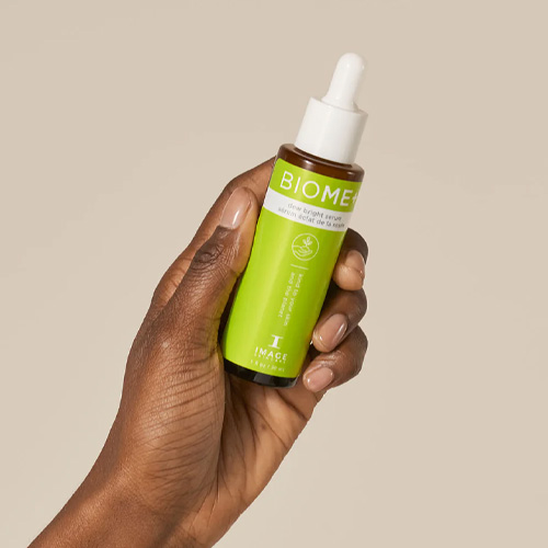 Een model brengt het BIOME+ Dew Bright Serum aan voor een gehydrateerde, stralende huid.