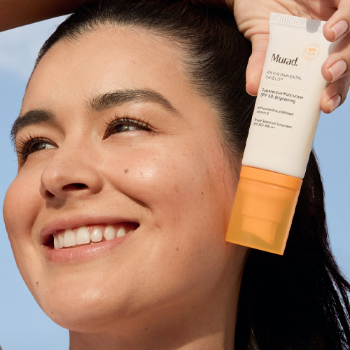 Vrouw met stralende huid die Murad Environmental Shield Superactive Moisturizer SPF 50 vasthoudt