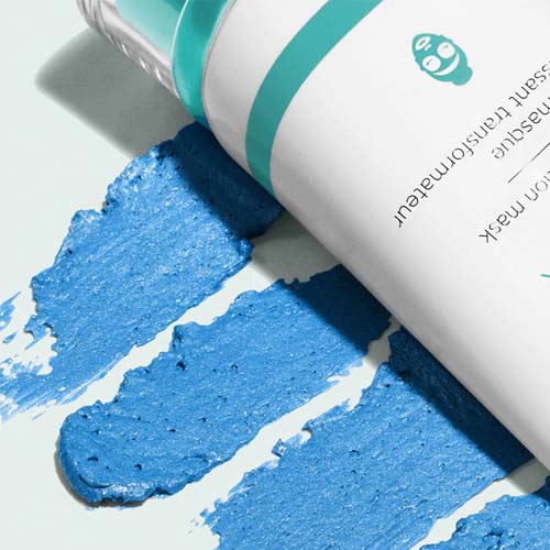 De witte tube van het Firming Transformation Masker liggend bovenop drie brede, blauwe textuurvegen van het product.