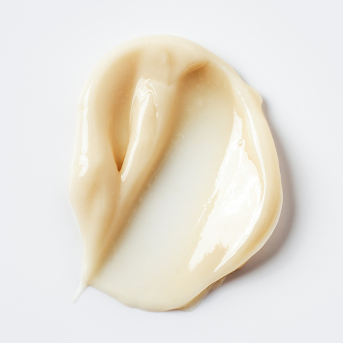 Een close-up swatch van de IMAGE Skincare MD Biotech Longevity Crème, die een rijke, romige en licht beige textuur laat zien.