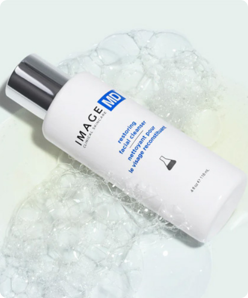 Witte flacon van IMAGE Skincare IMAGE MD restoring facial cleanser liggend in wit schuim.