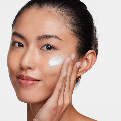 Model smeert HydroPeptide Solar Dew zonnebrandcrème uit op haar gezicht
