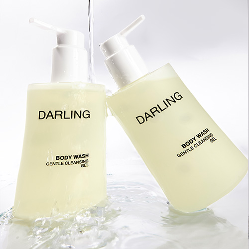 Twee flessen DARLING Body Wash waar water overheen stroomt, wat zorgt voor een fris en hydraterend effect.