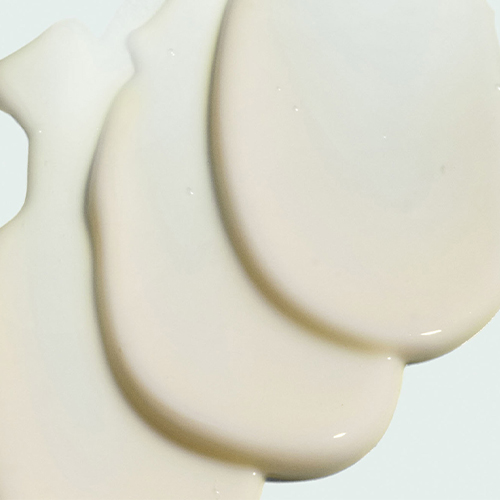 Drie dikke banen van de witte, romige VITAL C Hydrating Hand and Body Lotion textuur op een lichte achtergrond.