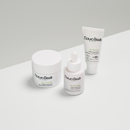 Drie Natura Bissé NB Ceutical huidverzorgingsproducten waaronder een pot crème een serum met pipet en een tube zonnebrandcrème op een strakke witte achtergrond